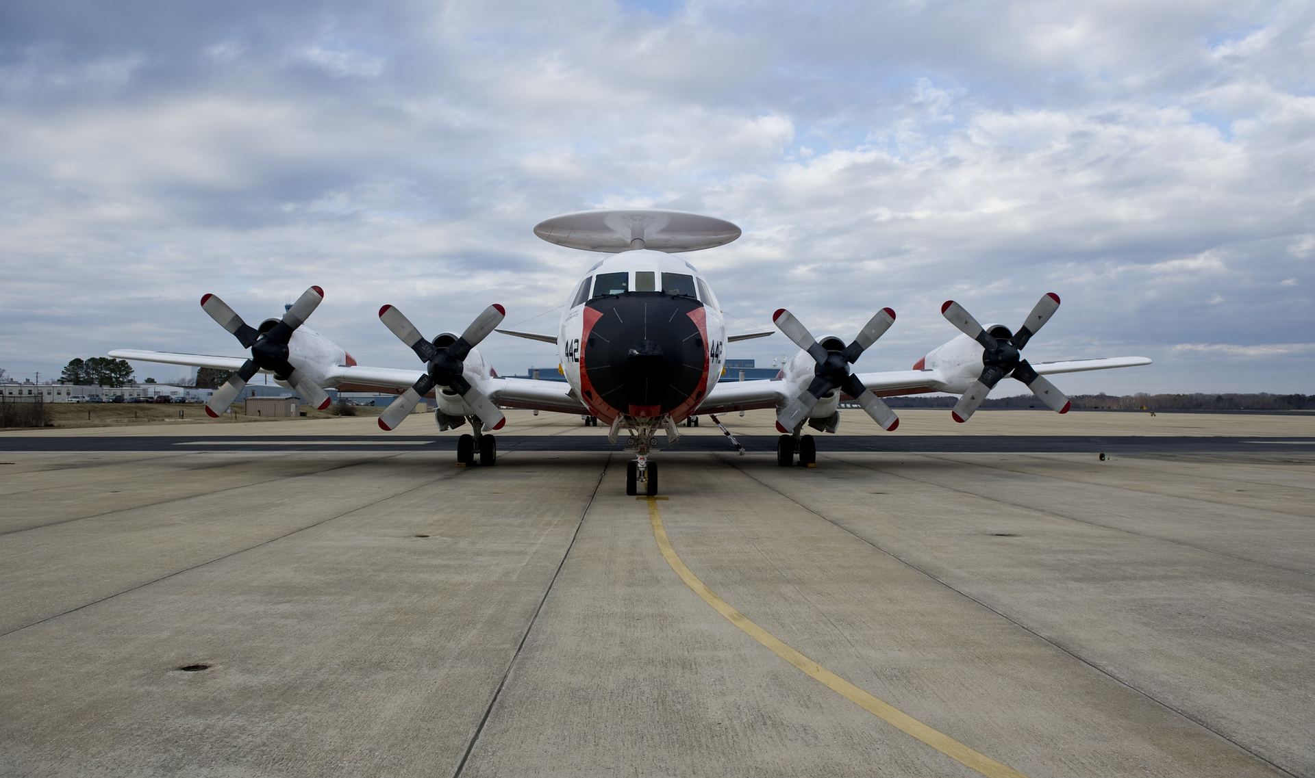 A Navy research aircraft with a rotating radar dome parked on the flight line